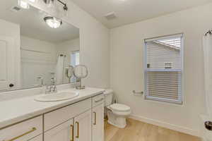 Full bathroom featuring toilet, visible vents, wood finished floors, and vanity