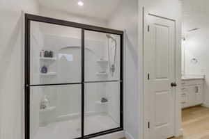 Full bathroom featuring visible vents, wood finished floors, a shower stall, and vanity