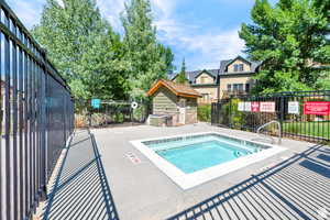 View of pool with a community hot tub and fence