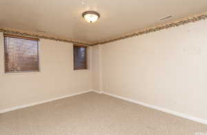 Unfurnished room with carpet floors, visible vents, a textured ceiling, and baseboards