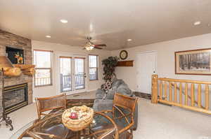 Living area featuring recessed lighting, carpet, a textured ceiling, and a stone fireplace