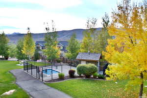 Surrounding community featuring a pool, a mountain view, a lawn, and fence