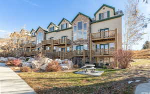 Exterior space featuring a balcony, stone siding, a patio, and french doors