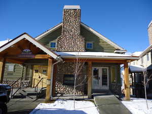 View of front of home featuring metal roof, stone siding, french doors, and a chimney