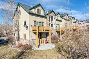 Back of property featuring stone siding, a patio area, and a residential view