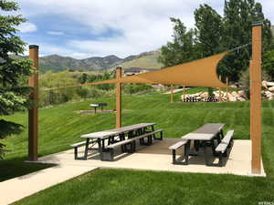 View of home's community featuring a patio area, a mountain view, and a lawn