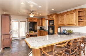 Kitchen featuring a breakfast bar, a sink, a peninsula, and black appliances