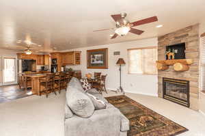 Living area with baseboards, ceiling fan, a stone fireplace, carpet floors, and recessed lighting