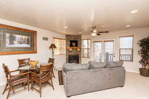 Living room featuring light carpet, baseboards, a ceiling fan, a fireplace, and recessed lighting