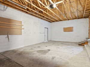 Below grade area with a garage, stairway, and concrete block wall