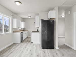 Kitchen with stainless steel appliances, a sink, white cabinetry, and baseboards