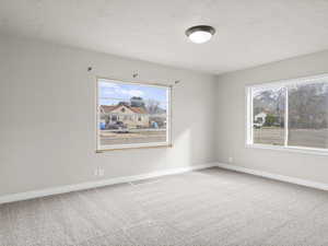 Carpeted empty room featuring visible vents, baseboards, and a textured ceiling