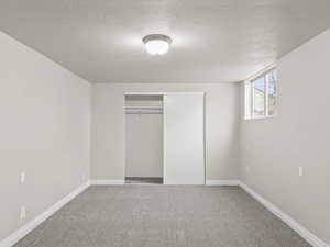 Unfurnished bedroom with carpet floors, a closet, a textured ceiling, and baseboards