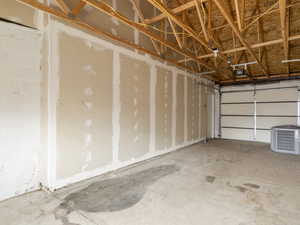 Garage featuring a garage door opener, concrete block wall, and central AC