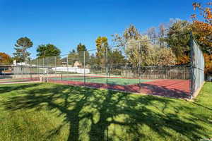 View of sport court featuring a yard and fence