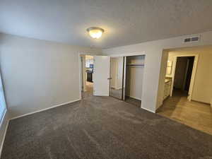 Unfurnished bedroom with a textured ceiling, a closet, visible vents, and baseboards