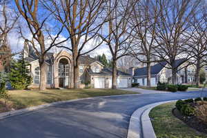 View of front of house with brick siding, a front yard, a garage, a residential view, and driveway