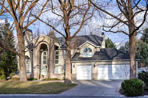 Traditional-style home featuring brick siding, a chimney, stucco siding, concrete driveway, and a garage