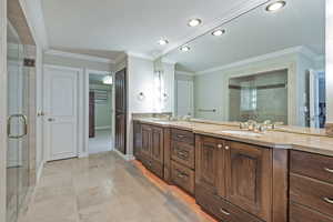 Bathroom featuring double vanity, a stall shower, and crown molding