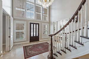 Tiled foyer featuring visible vents, stairway, a high ceiling, an inviting chandelier, and baseboards