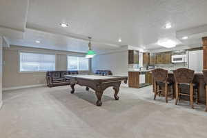 Game room featuring light carpet, billiards, a textured ceiling, and baseboards