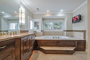 Bathroom featuring recessed lighting, vanity, a bath, and crown molding