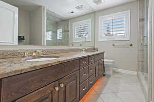 Full bath with tile patterned flooring, a sink, visible vents, a shower stall, and double vanity