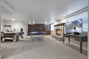 Playroom with a brick fireplace, baseboards, a textured ceiling, and light colored carpet