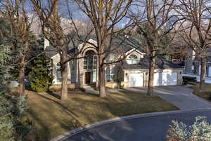 View of front of home with an attached garage, driveway, and a front lawn