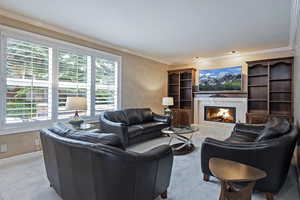 Living area featuring ornamental molding, a fireplace, carpet flooring, and baseboards