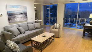 Living area featuring ornamental molding, a wall of windows, and wood finished floors