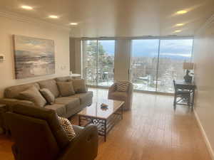 Living area featuring baseboards, floor to ceiling windows, crown molding, and wood finished floors