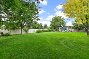 View of yard featuring a playground and a fenced backyard