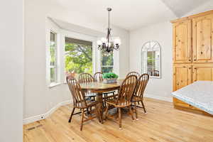 Dining room featuring a chandelier, light wood-type flooring, visible vents, and baseboards