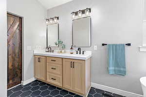 Bathroom with double vanity, baseboards, and a sink