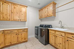 Clothes washing area with light tile patterned floors, cabinet space, visible vents, a sink, and washer and dryer