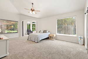 Carpeted bedroom with vaulted ceiling, ceiling fan, and baseboards