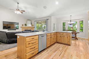 Kitchen with vaulted ceiling, light countertops, a sink, and stainless steel dishwasher