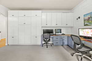 Office area with ornamental molding, built in study area, and light colored carpet