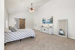 Bedroom featuring light colored carpet, a barn door, ceiling fan, high vaulted ceiling, and baseboards