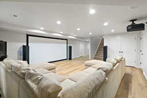 Home theater featuring recessed lighting, baseboards, visible vents, and light wood finished floors