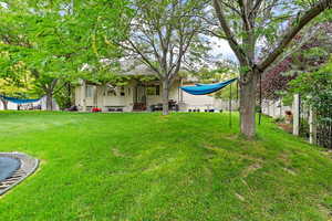 View of yard featuring a trampoline, entry steps, and fence