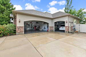 View of property exterior featuring a garage, concrete driveway, and brick siding