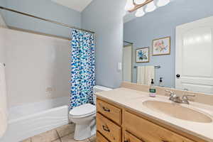 Full bathroom with toilet, tile patterned flooring, shower / bath combo, and vanity