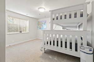 Carpeted bedroom with visible vents, a textured ceiling, and baseboards