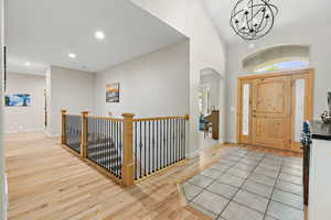 Entryway featuring baseboards, arched walkways, light wood-style floors, a chandelier, and recessed lighting