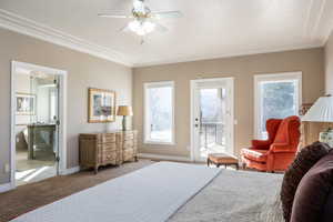 Bedroom with ensuite bathroom, carpet floors, baseboards, access to exterior, and crown molding