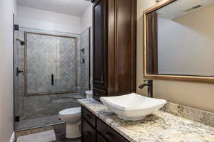 Full bathroom with a stall shower, visible vents, toilet, a textured ceiling, and vanity