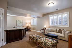 Living room with a healthy amount of sunlight, visible vents, light carpet, and baseboards