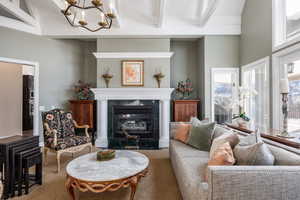 Living area with a fireplace, beamed ceiling, and an inviting chandelier